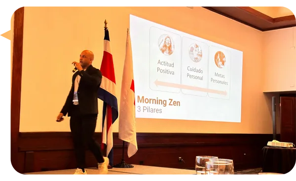 Adrián González en tarima con apoyo visual durante una presentación.